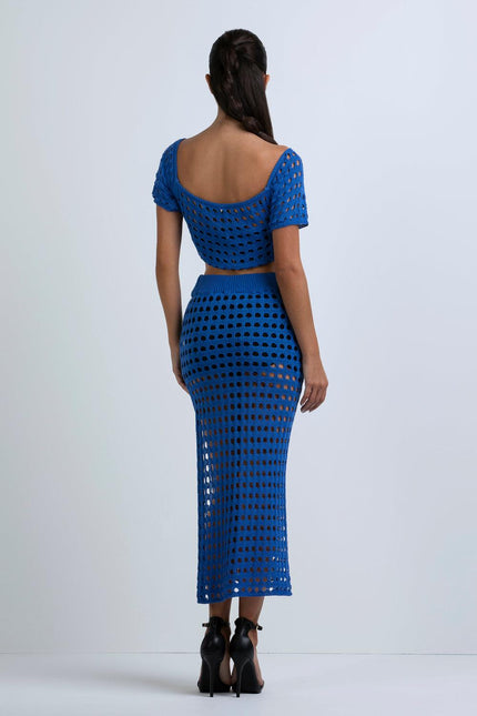 Woman wearing a blue crochet knit crop top and matching midi skirt, back view