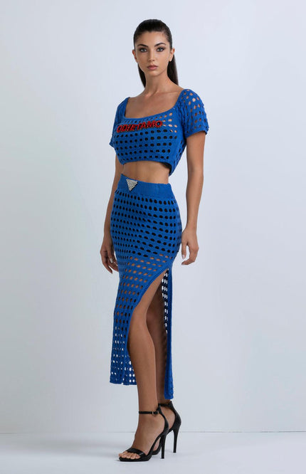 Woman wearing a blue crochet crop top and high-slit skirt set with cutout details