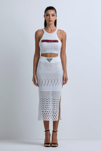 Woman wearing white crochet crop top and midi skirt set with cutouts and red text detail