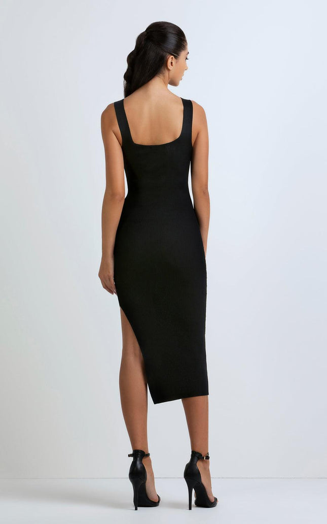 Woman in black sleeveless bodycon midi dress with side slit and high heels, back view