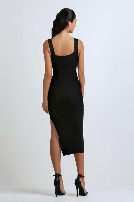 Woman in black sleeveless bodycon midi dress with side slit and high heels, back view