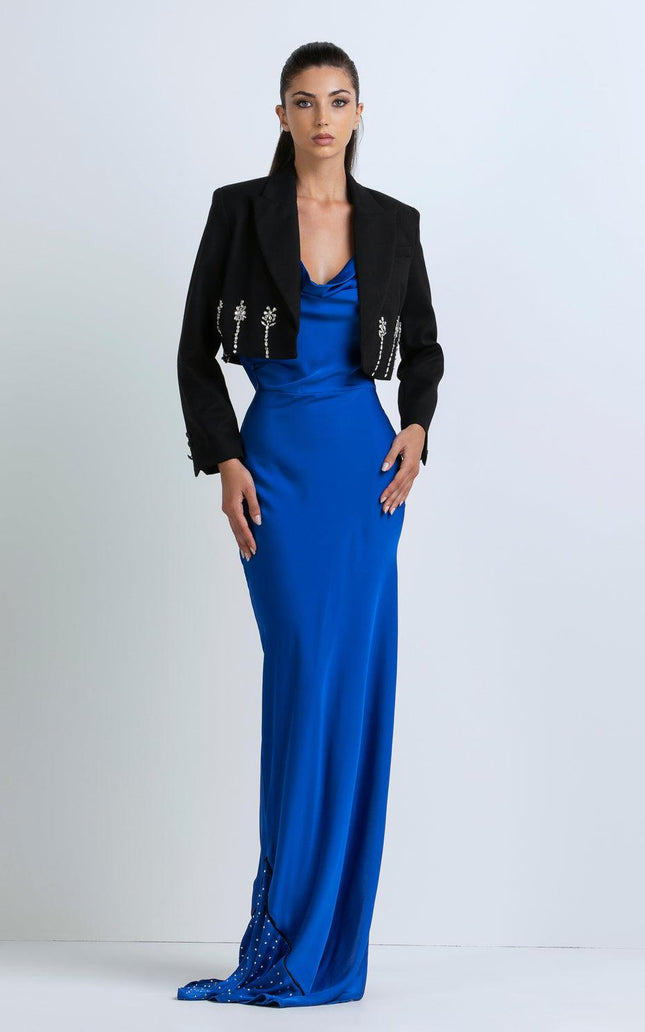 Woman wearing a royal blue satin evening gown and cropped black jacket with jeweled accents