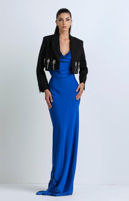 Woman wearing a royal blue satin evening gown and cropped black jacket with jeweled accents