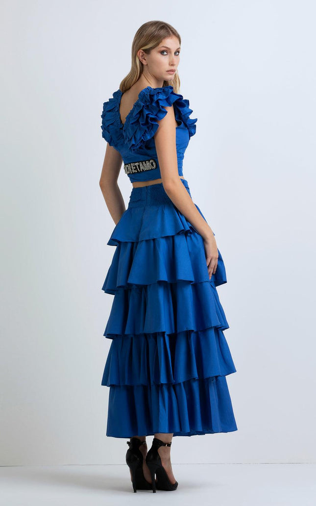 Woman in blue ruffled crop top and tiered maxi skirt, posing in high heels