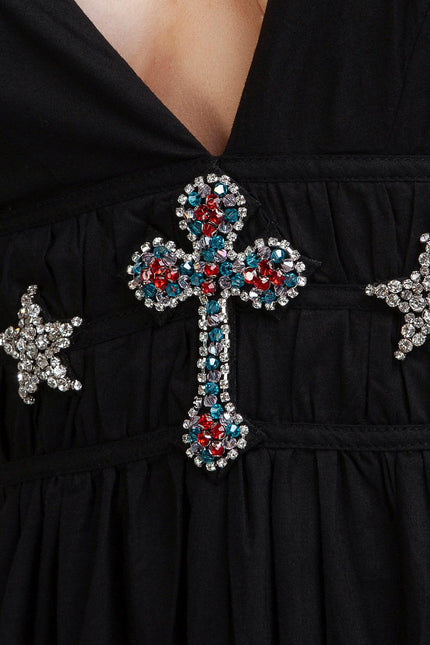 Close-up of a black dress with colorful rhinestone cross and star embellishments