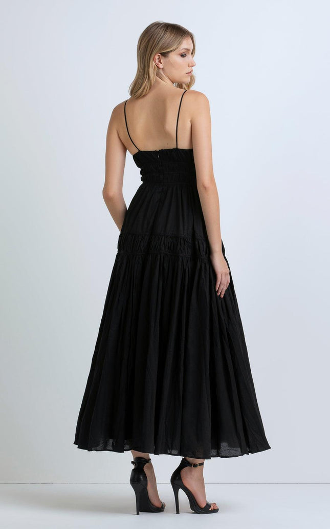 Woman in a black maxi dress with thin straps and high heels, shown from the back