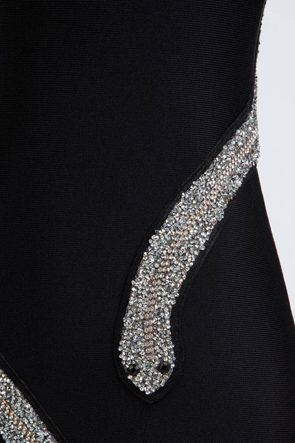Close-up of black fabric dress with sparkling rhinestone snake applique detail