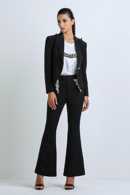 Woman wearing black flared pants, black blazer with sequin details, and white graphic tee
