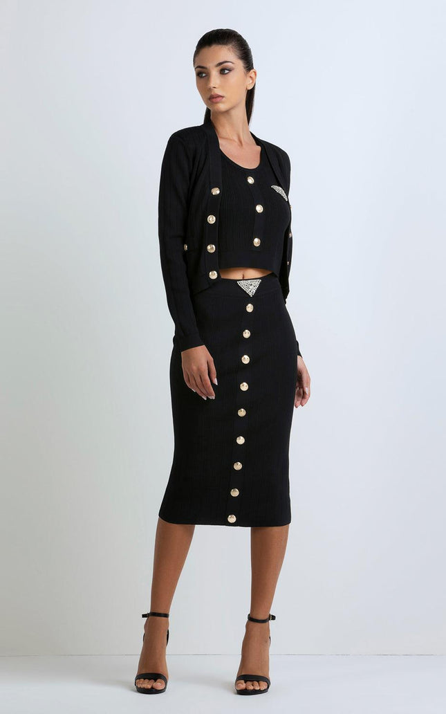 Woman wearing a black ribbed three-piece set with gold buttons and rhinestone accents