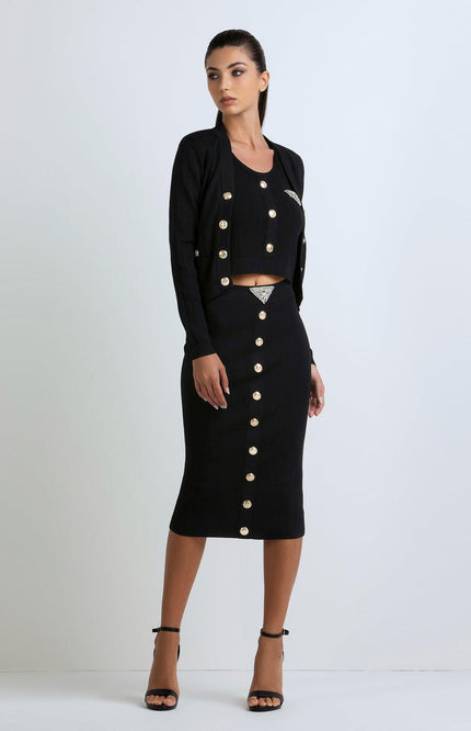 Woman wearing a black ribbed three-piece set with gold buttons and rhinestone accents