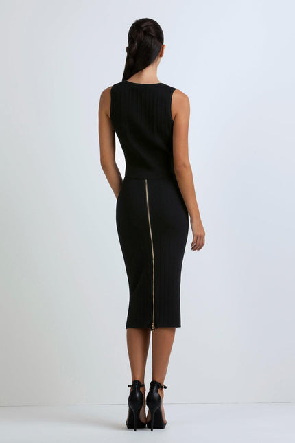 Woman in sleeveless black ribbed dress with back zipper detail and high heels