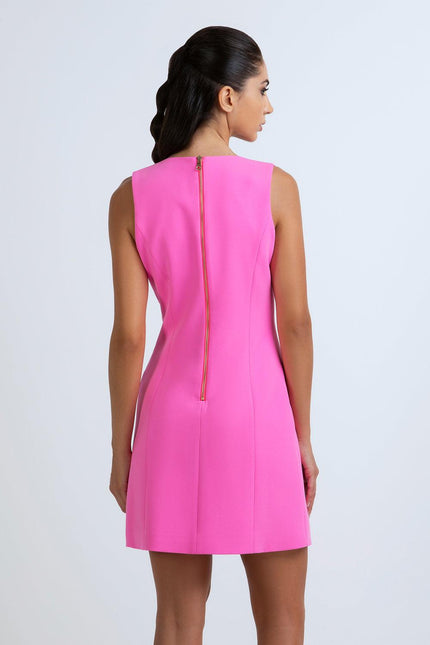 Woman in a sleeveless hot pink mini dress with visible back zipper, studio background