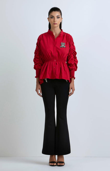 Woman wearing a red ruched sleeve blouse with embroidered detail and black flared pants