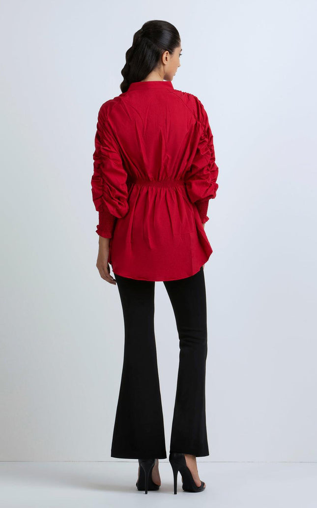 Woman wearing a red ruched long-sleeve blouse and black flared pants