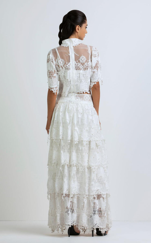 Woman wearing a long white lace maxi dress with sheer short sleeves, seen from behind
