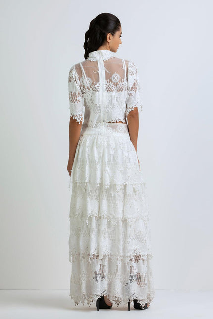 Woman wearing a long white lace maxi dress with sheer short sleeves, seen from behind