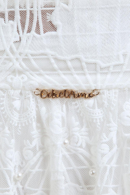 White lace fabric with embroidery, pearl accents, and gold script detail