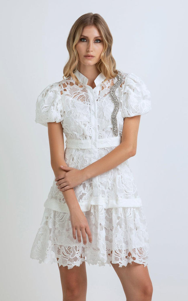 Woman wearing a white lace dress with puff sleeves and rhinestone detail, fashion photo