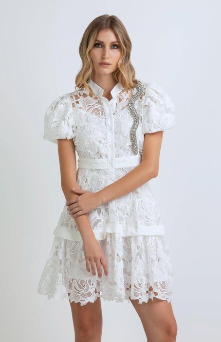 Woman wearing a white lace dress with puff sleeves and rhinestone detail, fashion photo