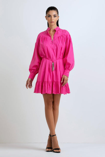 Woman wearing a hot pink mini dress with long sleeves, ruffle hem, and eyelet details