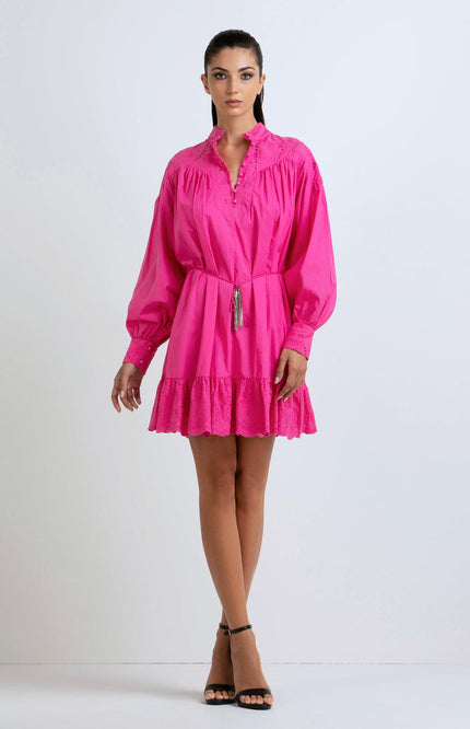 Woman wearing a hot pink mini dress with long sleeves, ruffle hem, and eyelet details
