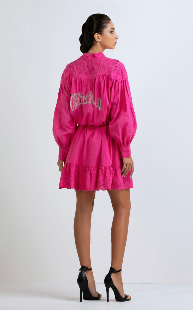 Woman in vibrant pink mini dress with embroidered back, long sleeves, and ruffle hem