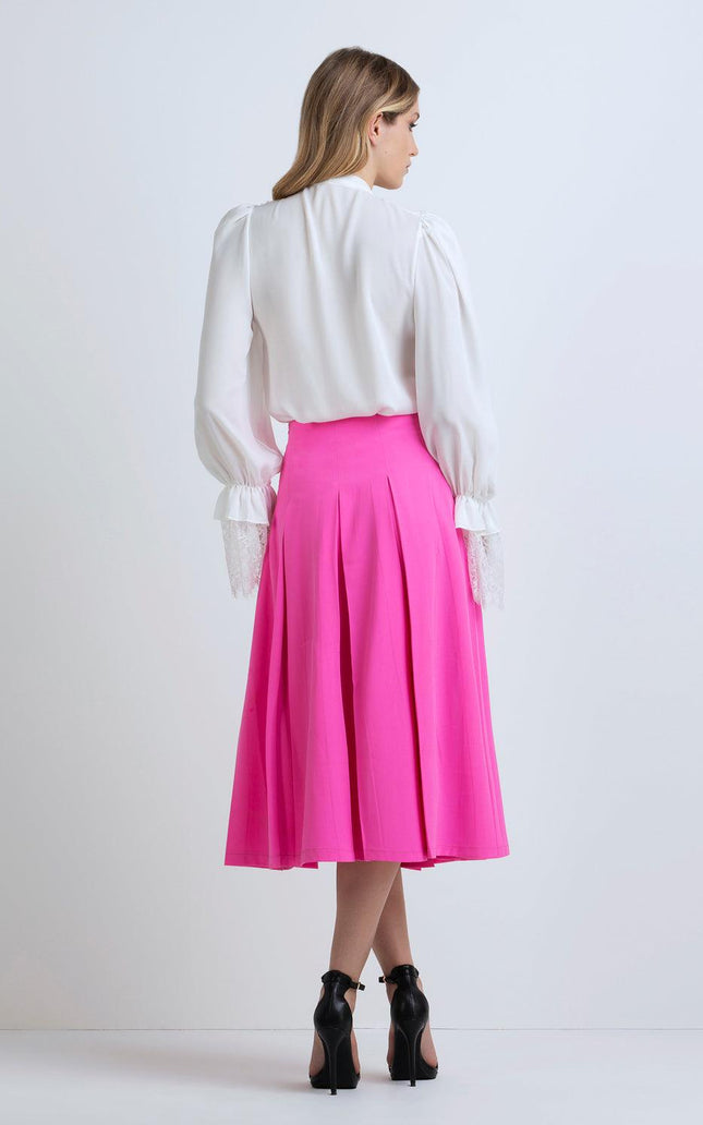 Woman wearing white blouse and bright pink pleated midi skirt with black high heels