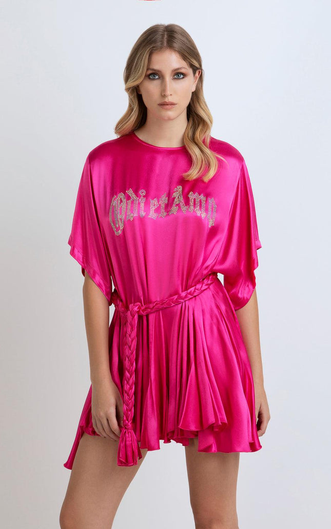 Woman wearing a hot pink satin mini dress with braided belt and crystal lettering