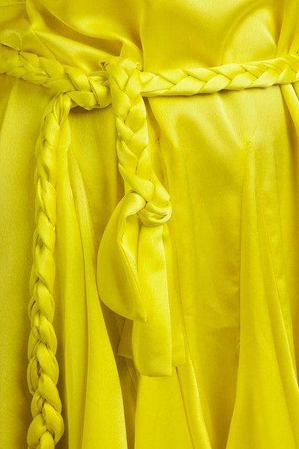 Close-up of yellow satin dress with braided belt and pleated fabric details