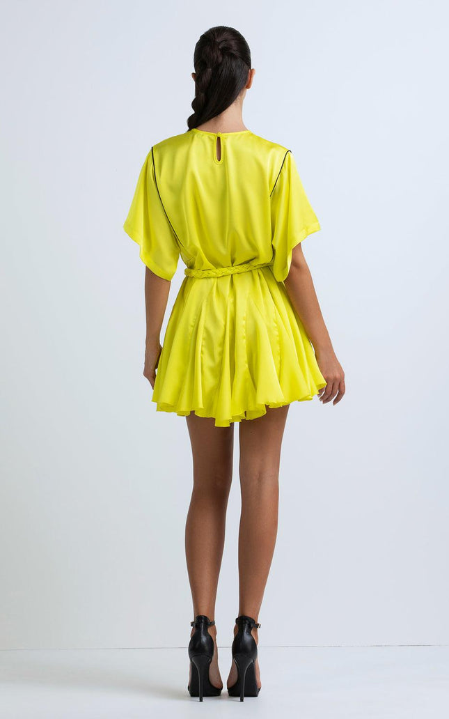 Back view of woman in short yellow belted dress with flutter sleeves and high heels