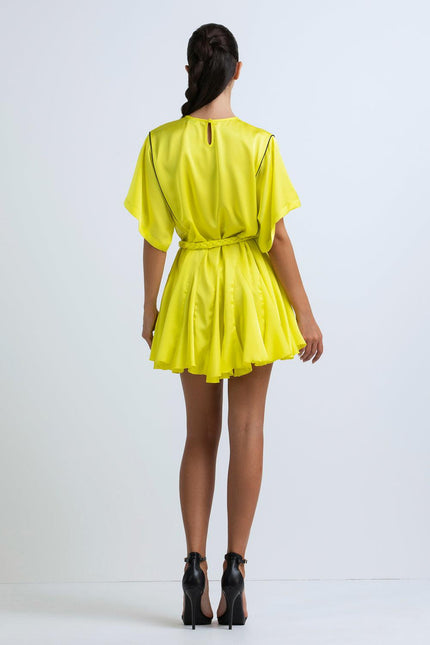Back view of woman in short yellow belted dress with flutter sleeves and high heels