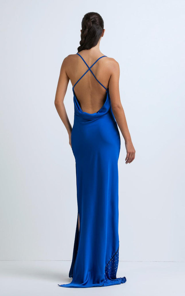 Woman in blue satin maxi dress with open back, criss-cross straps, and side slit