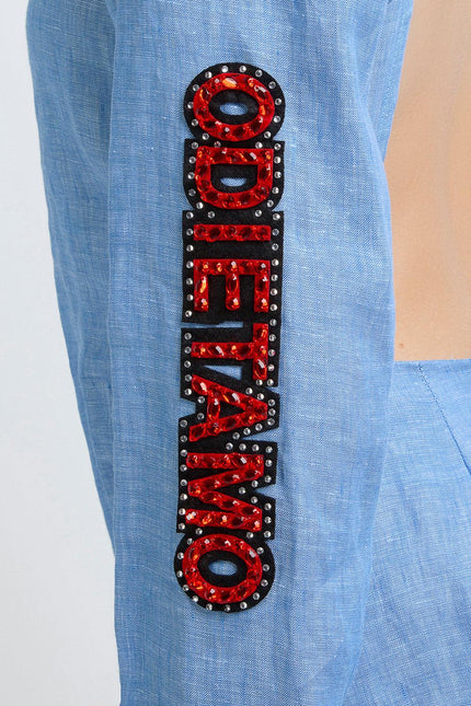 Blue sleeve with red sequin ODI ET AMO lettering and rhinestone embellishments