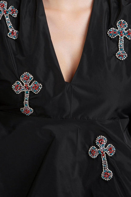 Black dress with deep V-neck and gemstone-embellished cross details, close-up view