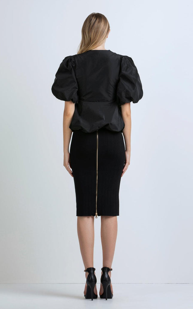 Woman wearing black puff sleeve blouse and fitted pencil skirt with back zipper