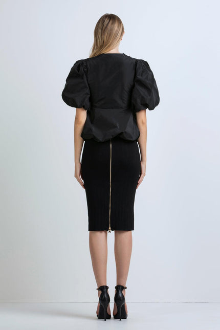 Woman wearing black puff sleeve blouse and fitted pencil skirt with back zipper