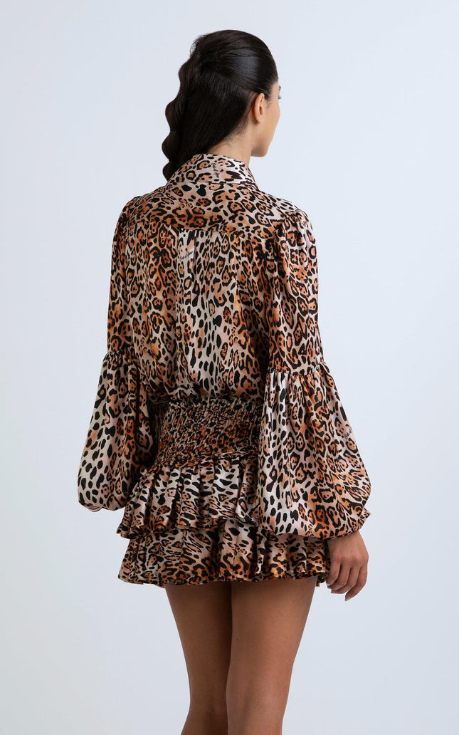 Woman wearing a leopard print mini dress with ruffled skirt and long sleeves, rear view