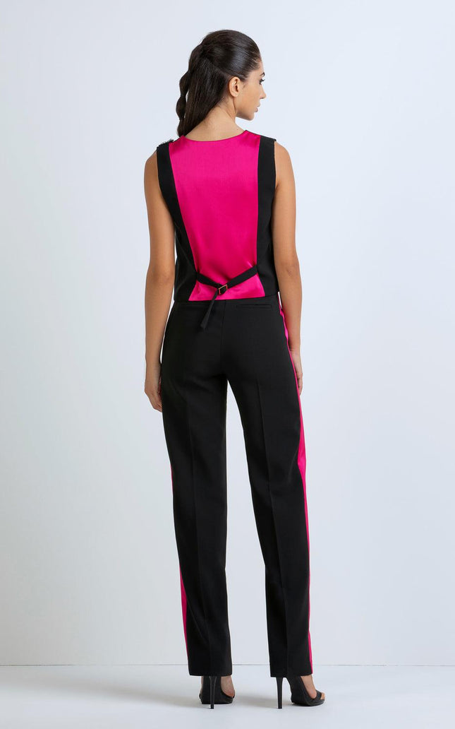 Woman wearing a sleeveless black and fuchsia jumpsuit with color block design, rear view