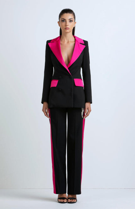 Woman wearing black pantsuit with bold pink lapels and pocket accents, front view