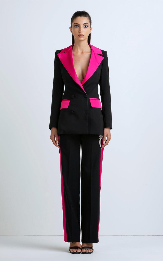 Woman wearing a black suit with hot pink lapels and side stripes, standing against a plain background