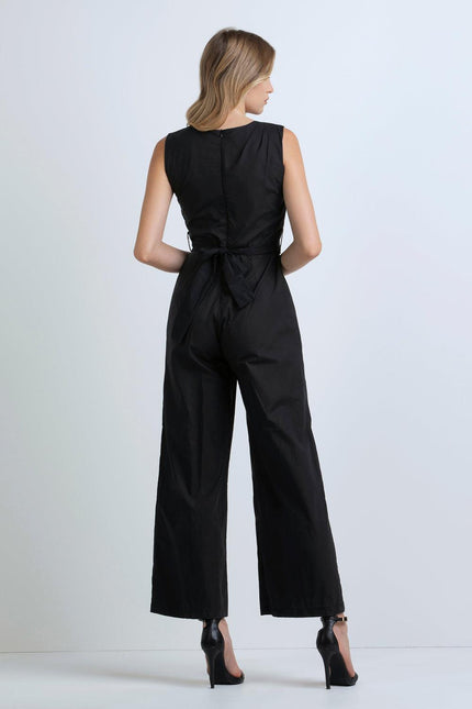 Woman in sleeveless black jumpsuit with tied waist and wide legs, back view
