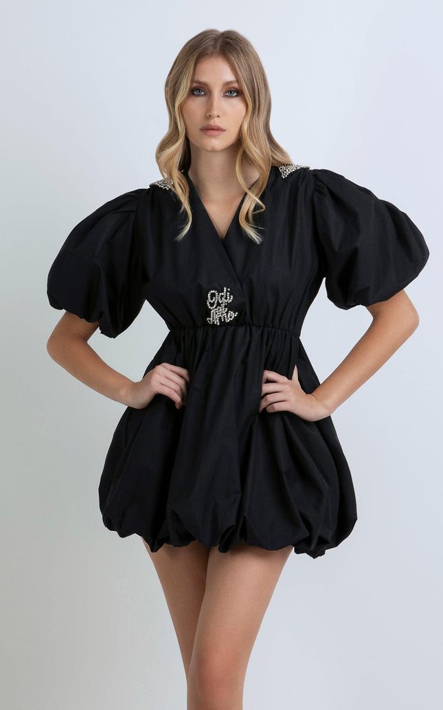 Woman wearing a black puff sleeve mini dress with pearl details and Odi et Amo embroidery
