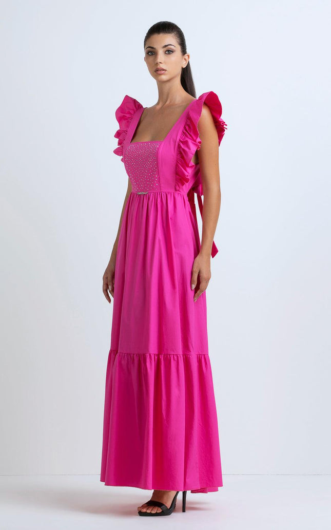 Woman in a bright pink maxi dress with ruffled straps and studded bodice, studio background