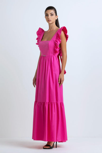Woman in a bright pink maxi dress with ruffled straps and studded bodice, studio background