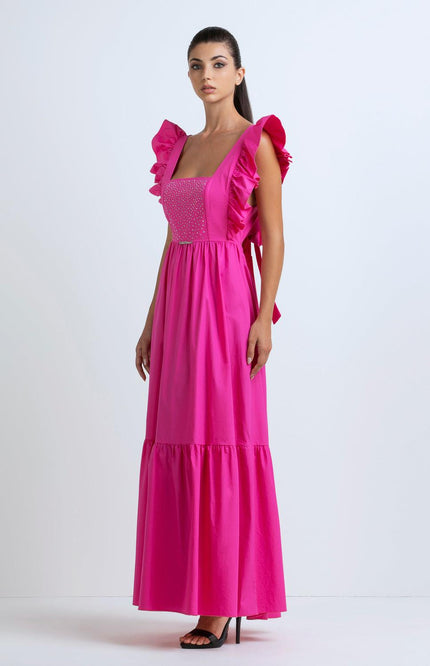Woman in a bright pink maxi dress with ruffled straps and studded bodice, studio background