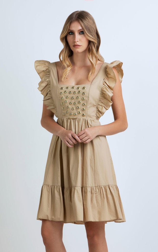 Woman wearing beige ruffle dress with gold stud details, square neckline, and flared skirt