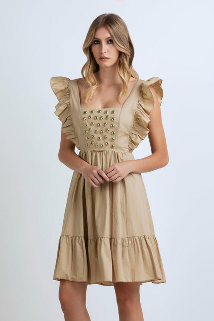 Woman wearing beige ruffle dress with gold stud details, square neckline, and flared skirt