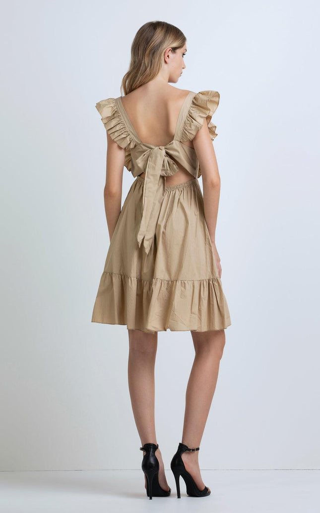 Woman wearing beige ruffle sleeve dress with open back and bow detail, high heels