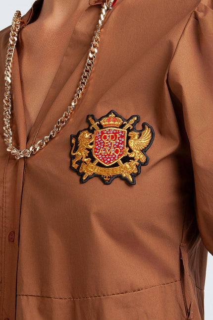 Brown shirt with gold chain and embroidered red and gold crest patch on chest