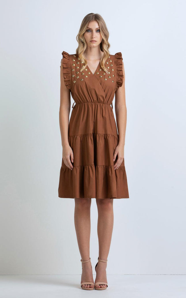 Woman in brown sleeveless ruffle dress with gold studs, tiered skirt, neutral heels